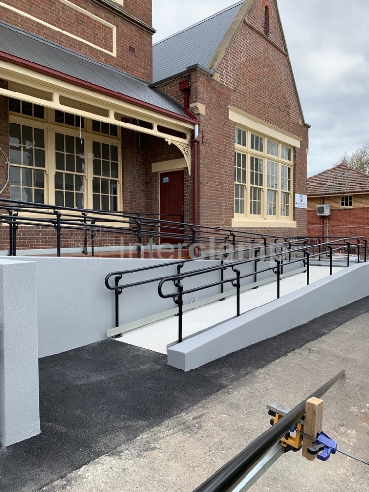 Black powder coated modular handrails installed on school access ramp.